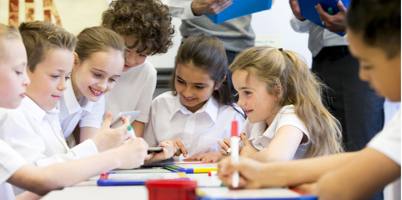 A group of school children can be seen working on digital tablets and whiteboards, they are all working happily (1)