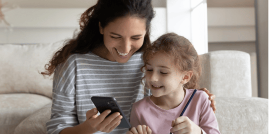 Find a role model mother and daughter smiling whilst looking at mobile phone