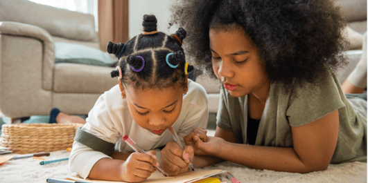 Happy African mixed race family. Cute child girl kid sibling lying on the floor using color pencil drawing