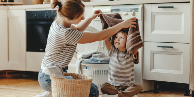 Happy family mother housewife and child son in laundry with washing machine