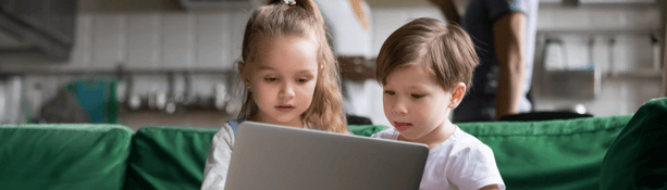 young siblings looking at laptop during lockdown