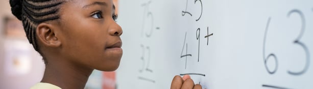 Girl writing sum on school whiteboard