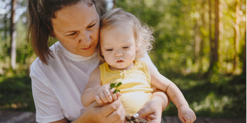 Little cute baby toddler girl blonde with curls on mothers arms