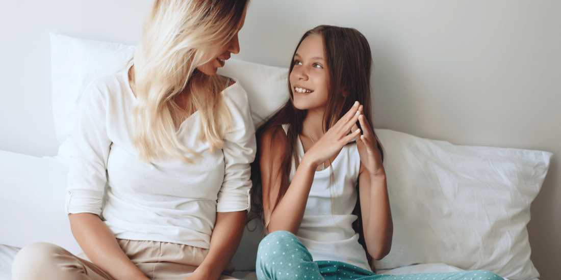 Mum and daughter relaxing in bed, talking about their day. 