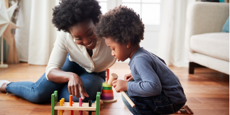 Mother and toddler son playing with toys on the floor