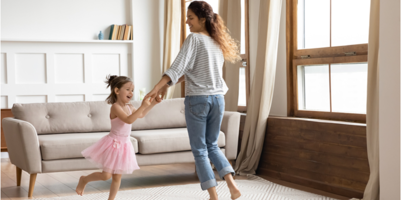Mum and daughter dancing together in living room