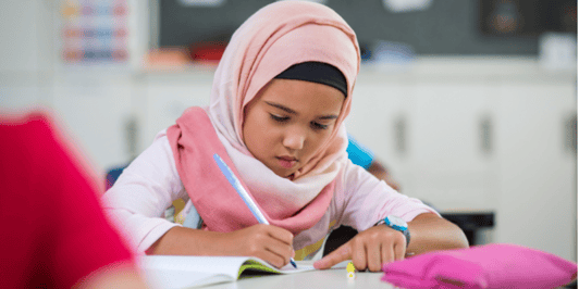 What is a language disorder_ Young Muslim girl sat at her desk doing school work