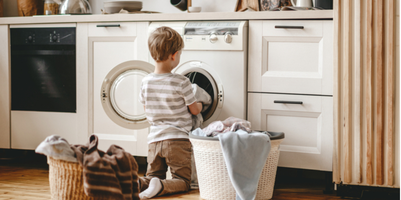 unrecognizable little householder child boy in laundry with washing machine