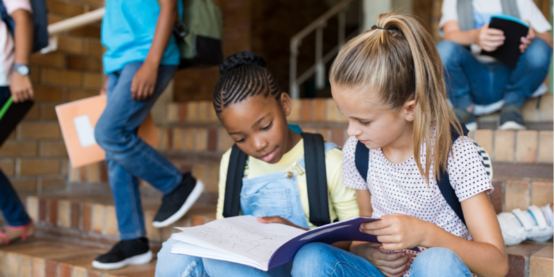 what is a reading disorder - 2 girls sat on school steps reading a book together