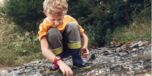 young boy picking up stones from a river