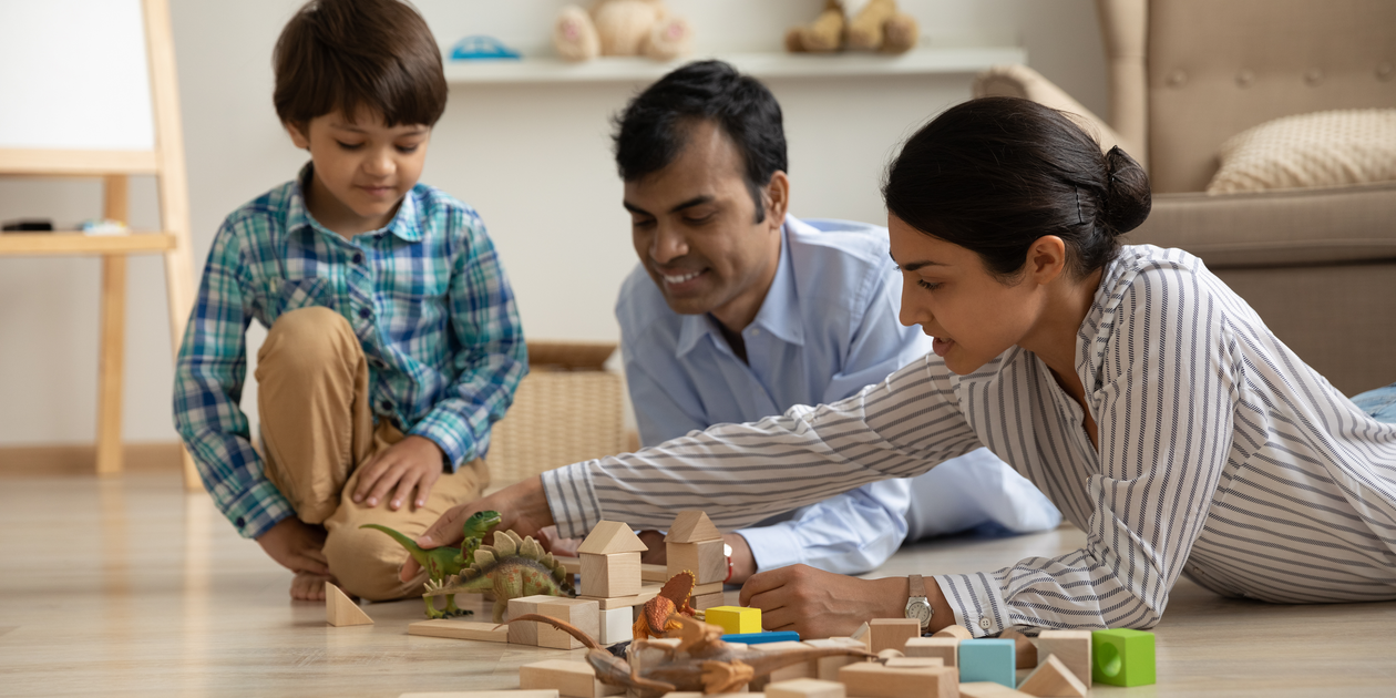 Young family playing blocks on the floor with their son